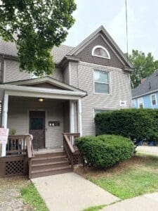Three-story brown house with front porch